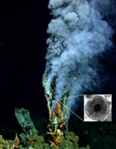 Hydrotermální průduch na mořském dně s vloženým snímkem částice pyritu.