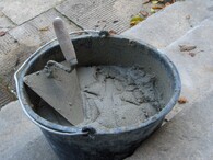 Lžíce v kbelíku s cementovou maltou.