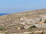 Pobřeží maltského ostrova Gozo s kamennými střílnami