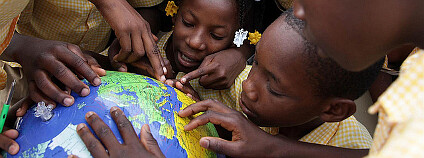 Děti si na globu ukazují země během hodiny v sirotčinci v haitském městě Jacmel. Ilustrační foto: UNICEF Canada