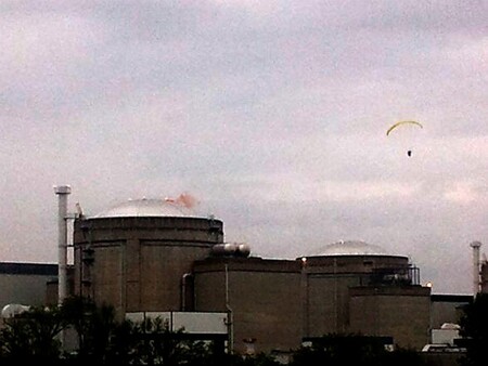 Aktivista Greenpeace hází dvě dýmovnice na budovy jaderné elektrárny Bugey