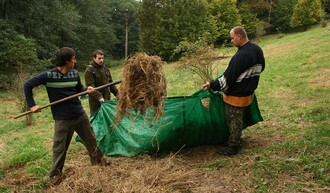 Dobrovolníci uklízejí posekanou trávu. Tato práce byla loni podpořena z programu PPK