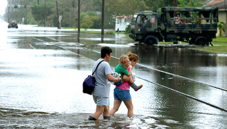 Žena nese holčičku při povodních, které přinesl hurikán Ike