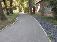 Cesta se sníženým obrubníkem, přes nějž srážková voda odtéká do boční štěrkové drenáže 