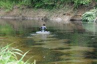 Muž se brodí znečištěnou řekou