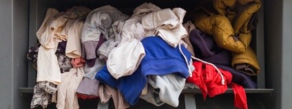 Špatně vhozený textil do sběrného kontejneru. Foto: Depositphotos