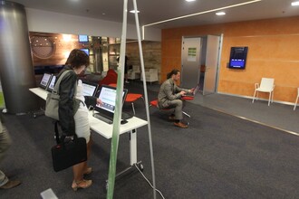 Účastnice konference prostřednictvím dotykového displaye zadává informace o způsobu dopravy. V pozadí Vladimír Kočí, který následně data zpracoval a vypočítal z nich uhlíkovou stopu konference.