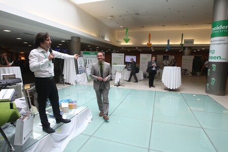 Jaroslav Pašmik s mikrofonem. Vladimír Kočí kráčí po skleněném pódiu, které bylo vyrobeno speciálně pro tuto konferenci. Na celkové uhlíkové stopě konference se jeho výroba podílela 0,3 %