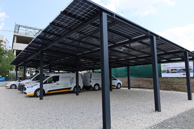 Přístřešek pro parkování aut - tzv. carport, jehož střechu tvoří solární panely a je napojen na ultrarychlou dobíjecí stanici pro elektromobily vybavenou akumulátorem.