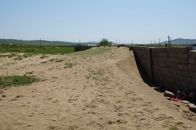 Vítr zanáší písek na nedalekou osadu. Zdejší ochrannou stěnu už písek téměř překonal.