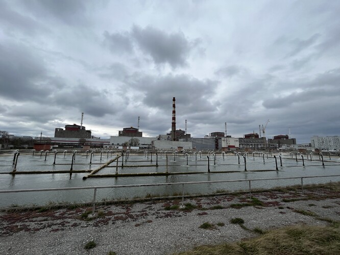 Na snímku jsou nádrže, ve kterých se rozprašováním ochlazuje ohřátá voda před opětovným použitím. Na pozadí je Záporožská jaderná elektrárna, snímek je z 29. března 2023.