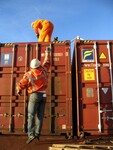 Přístavní dělníci připravují uložení dalšího kontejneru