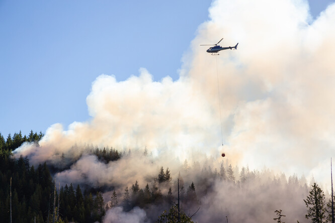 Vrtulník nad hořícím lesem.