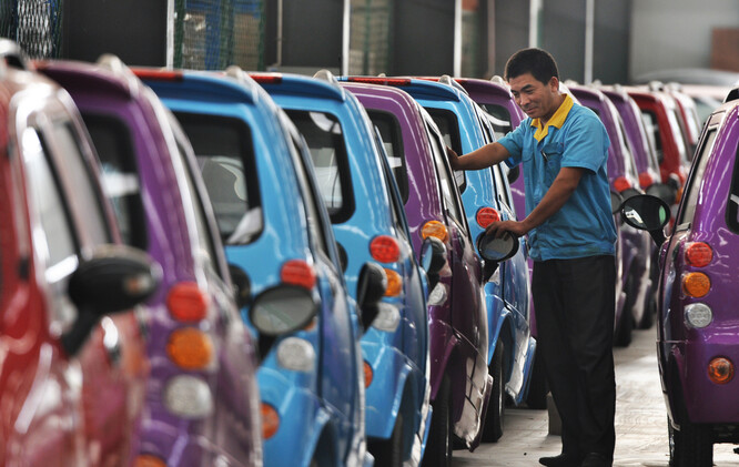 Čínský pracovník kontroluje elektromobily na montážní lince.