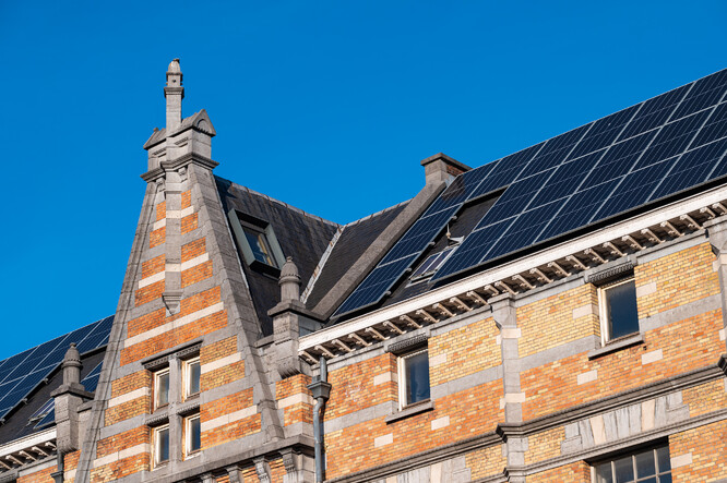 Historická fasáda budovy Tour and Taxis se solárními panely na střeše.