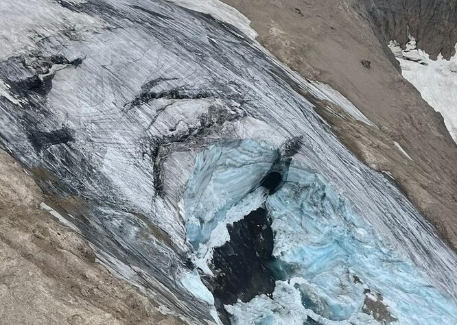 Všimněte si nad utrženou plochou černých pásů prasklin, které se v ledovci nachází