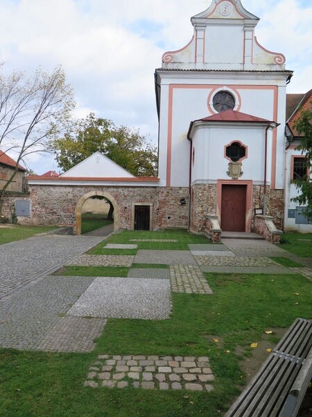 Pro zpevnění prostranství před kaplí v Dobřichovicích jsou použity dva druhy dlažby v kombinaci s trávníkem.