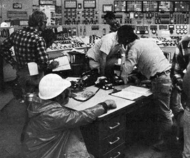 Jaderná elektrárna Three Mile Island, Pensylvánie, 1979. Řídicí místnost TMI-2 několik dní po začátku havárie. Muž v popředí s helmou na hlavě je Charles Gallina, inspektor americké Komise pro jaderný dozor. Dva muži nad Gallinou jsou Craig Faust a William Zewe, kteří byli v době havárie ve službě.